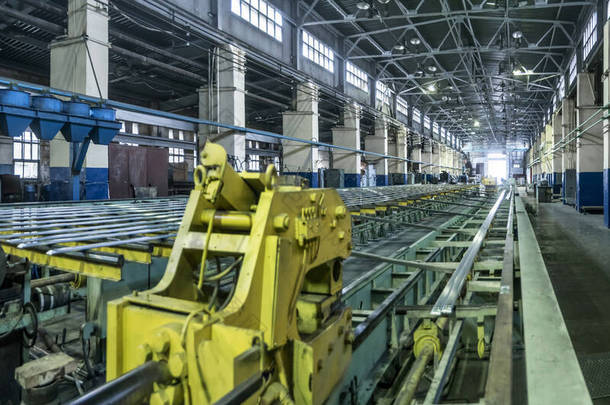 工厂的工业景观，一个巨大的车间，配备了机器、轧制和拉伸磨床，用于生产铝制金属和以长型材形式出现的空白.