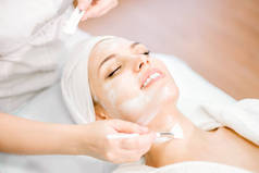 美容。美容师的手使用刷子进行清洁面膜。面部恢复手术