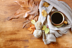 顶视图的杯黑咖啡，秋天的叶子，木制背景上温暖的围巾。filreted 图像