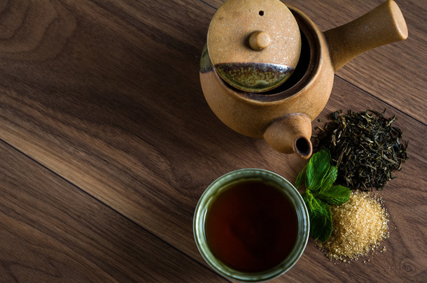 陶瓷茶壶，杯<strong>红茶</strong>薄荷叶和红糖木制的桌子上
