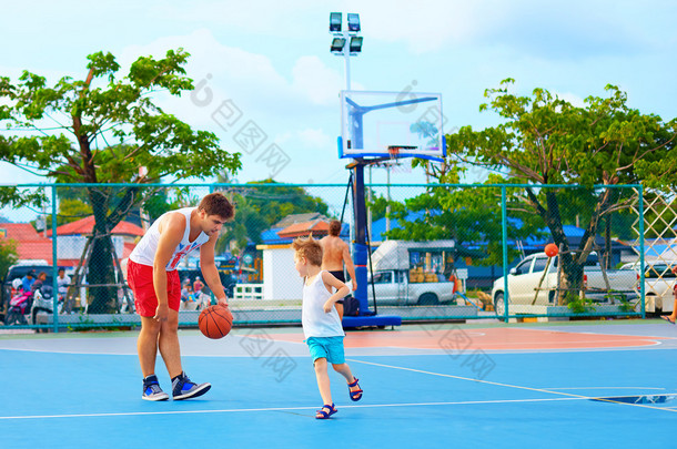 父亲和儿子在运动场上打篮球