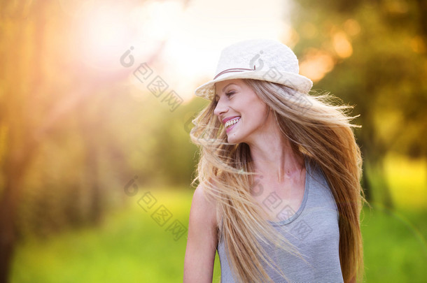 <strong>女人</strong>在笑在阳光明媚的公园里的白帽子