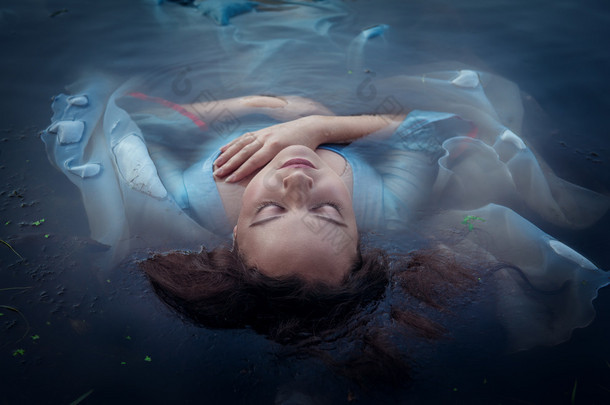 <strong>年轻</strong>美女穿着蓝色的衣服，躺在水中淹死