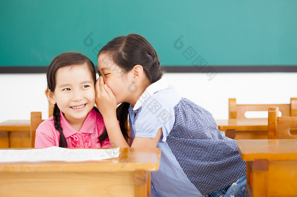 小女孩耳语和分享在教室里的秘密