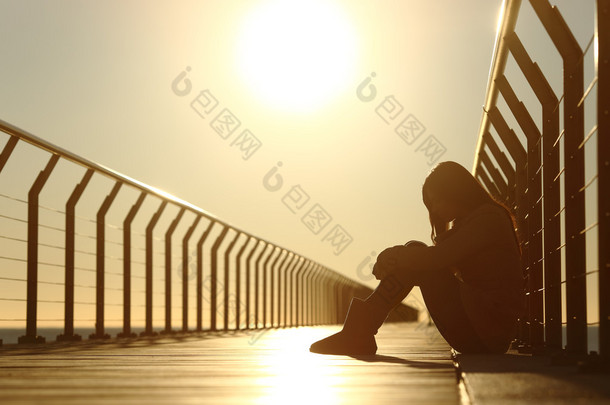 悲伤的十几岁的女孩沮丧在日落时分坐在<strong>一座</strong>桥