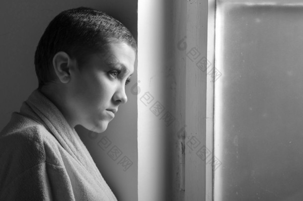 年轻的癌症病人站在医院的窗户