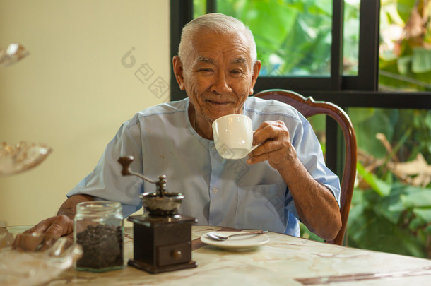 亚洲老人与老式的咖啡研磨机