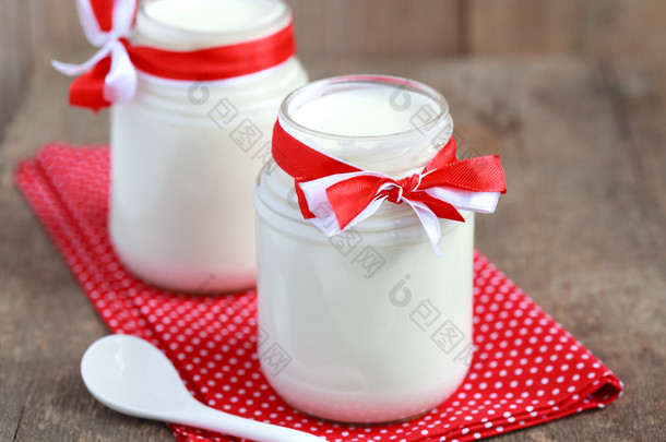自制酸奶在的木桌上的两个小玻璃罐。