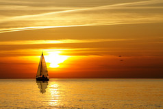 橙色调黄昏日落帆船海面图片
