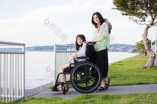 照顾妹妹坐在轮椅上的海滩