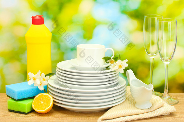 空清洁板材、 眼镜、 洗洁精、 海绵和柠檬绿色背景上的木桌上的杯子