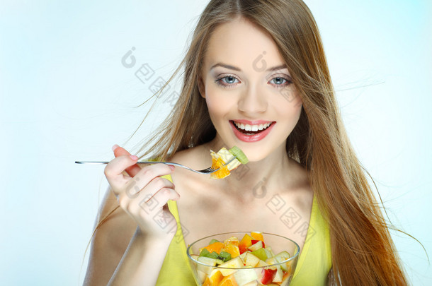 一个年轻漂亮的女人吃水果沙拉孤立在白色背景上的肖像