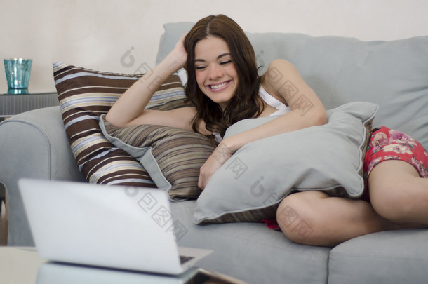 年轻可爱的女人在笔记本电脑上看电视