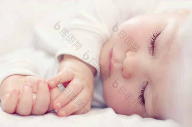 一个睡在白色<strong>床上</strong>的漂亮婴儿的特写