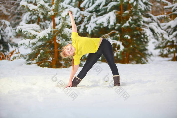 美丽的女人在户外在雪做瑜伽 