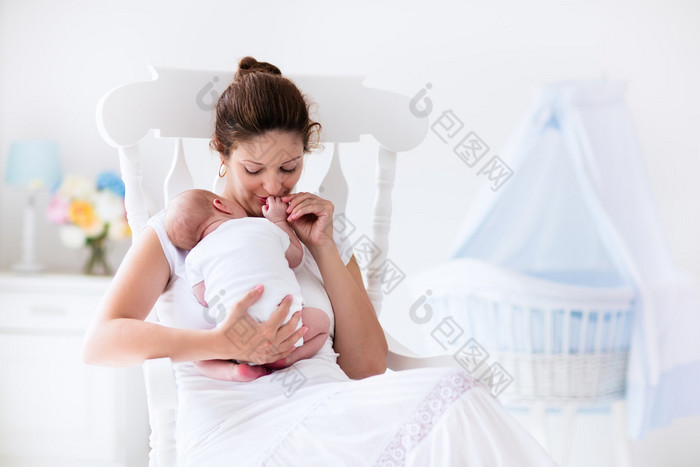 年轻的母亲和刚出生的婴儿在白色的卧室里