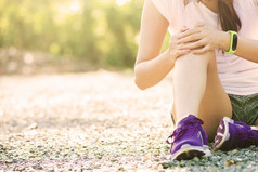 跑步运动膝关节损伤。同时在公园跑步的痛苦的女人