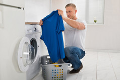使用洗衣机时穿着 t 恤的男人