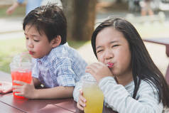 可爱的亚洲孩子饮用鲜榨果汁