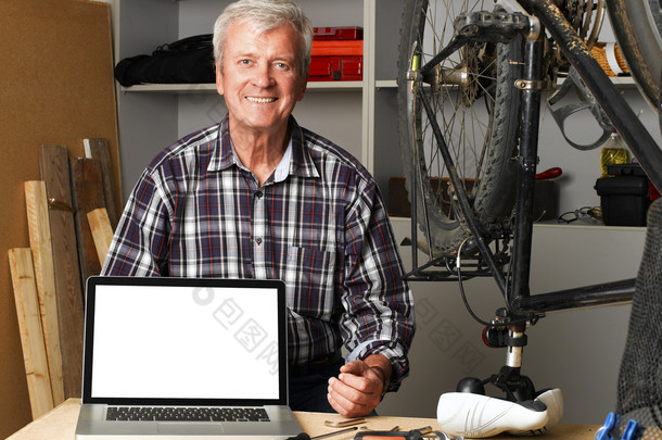 senior bike shop owner behind laptop