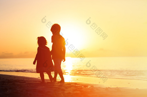 小男孩和女孩在日落海滩上行走