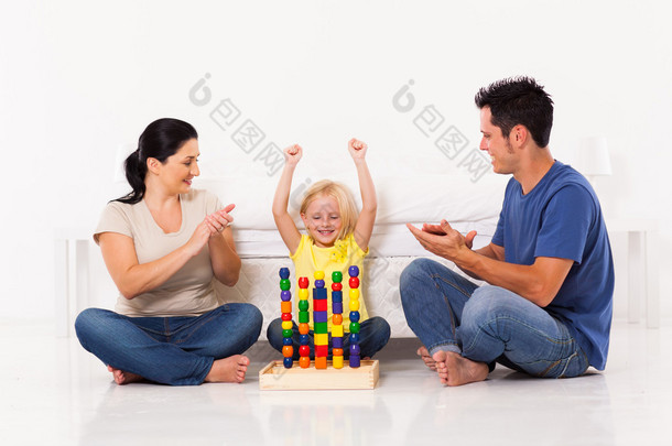 快乐的小女孩的卧室地板上玩的玩具，父母
