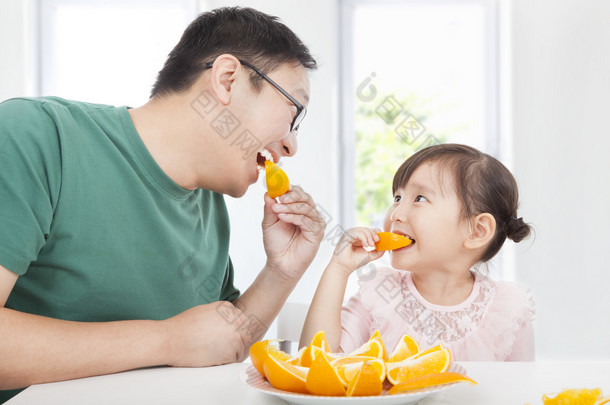 快乐的小女孩与父亲吃橙