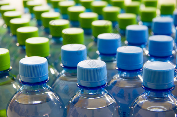 许多瓶清洁水的蓝色和绿色盖