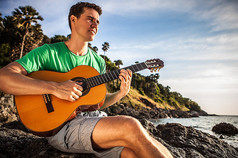 有吸引力的浪漫吉他弹奏者播放音乐选址上海滩岩.