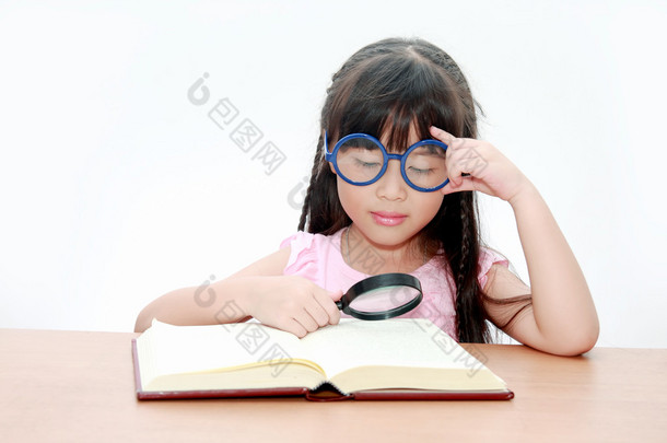 快乐的小亚洲女孩读本书戴着蓝色的眼镜，回