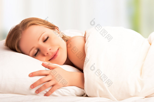 美丽的女人睡觉和他睡在床上的笑容