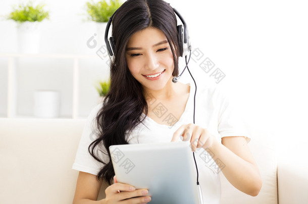 耳机和平板电脑在客厅里的年轻女子