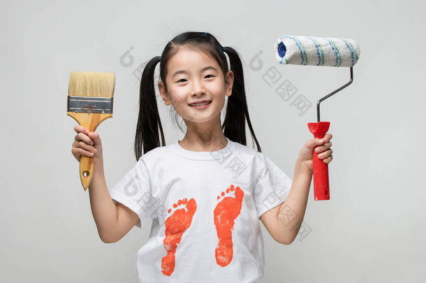 可爱的亚洲女孩抱着画笔和颜料的滚子.