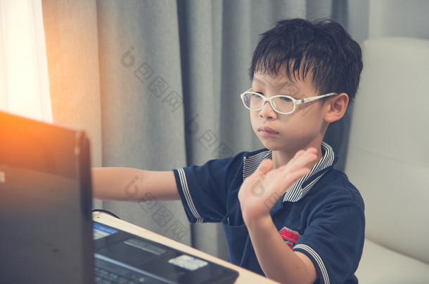 回到学校。亚洲男孩用他的笔记本电脑在家里