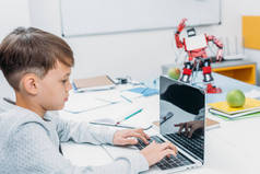 集中小学生打字在笔记本电脑键盘和编程机械机器人在茎类