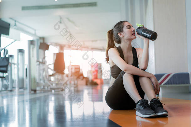 女子锻炼锻炼在健身房健身打破放松饮用蛋白质摇瓶训练运动健康生活方式健美后,