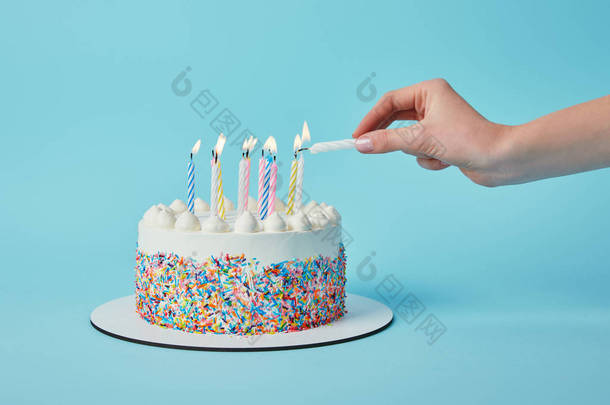 妇女点燃蜡烛的部份看法在生日蛋糕在蓝色背景