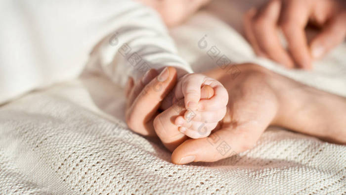 刚出生的婴儿抱着父亲的手指