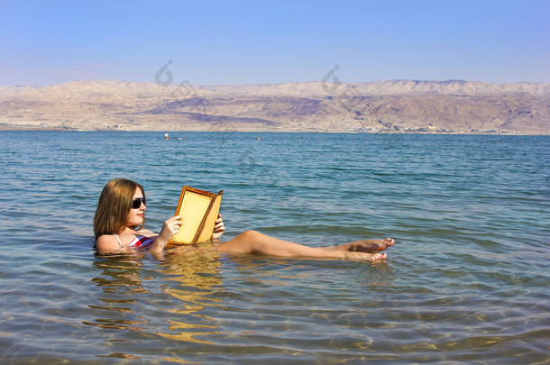年轻女孩看书漂浮在死海以色列