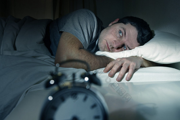 男人在床上用眼睛打开遭受失眠和睡眠障碍