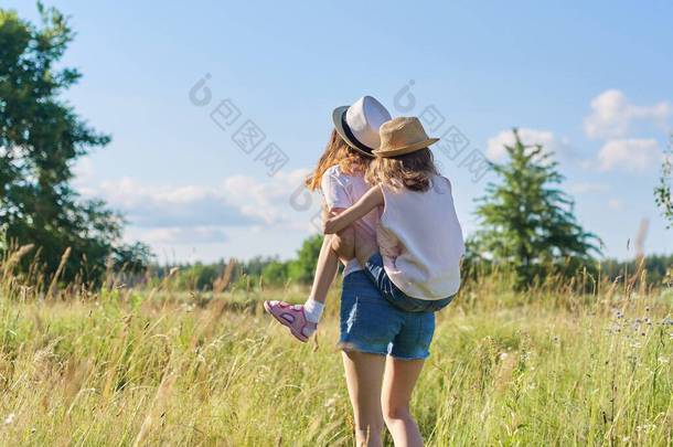 快乐的孩子，两个女孩妹妹，一个是少女，一个是少女，另一个是少女，笑着，在草地上玩的开心，<strong>蓝天</strong>，夏天的自然。积极健康的生活方式，友善的家庭，快乐的童年，复制的空间