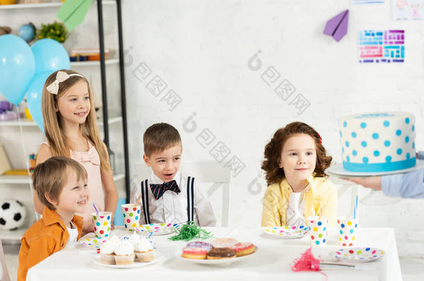 可爱的孩子们坐在桌旁等待<strong>蛋糕</strong>在生日聚会