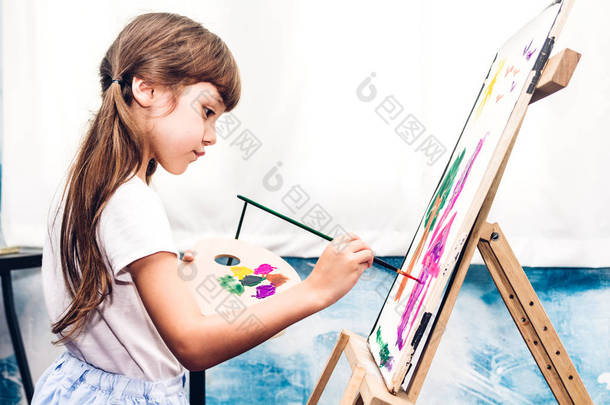 小女孩画家在画布上画画，家里有<strong>彩色</strong>调色板和水彩画