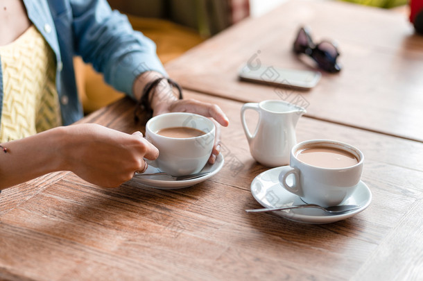 两杯咖啡和女人手在咖啡厅的木桌上 