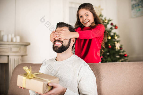 微笑的女儿覆盖父亲的眼睛从后面