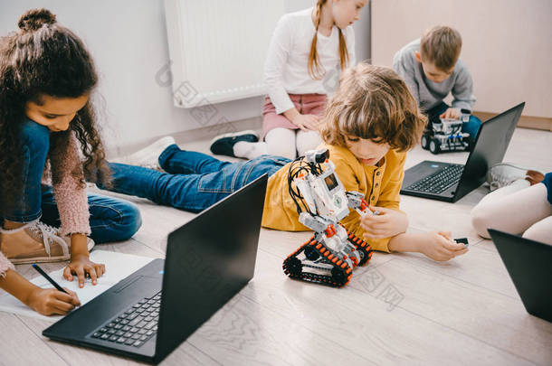 小孩子们坐在地板上用膝上型电脑编程干细胞教育理念