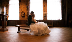 新郎和新娘坐在长椅上反对在古堡的窗口