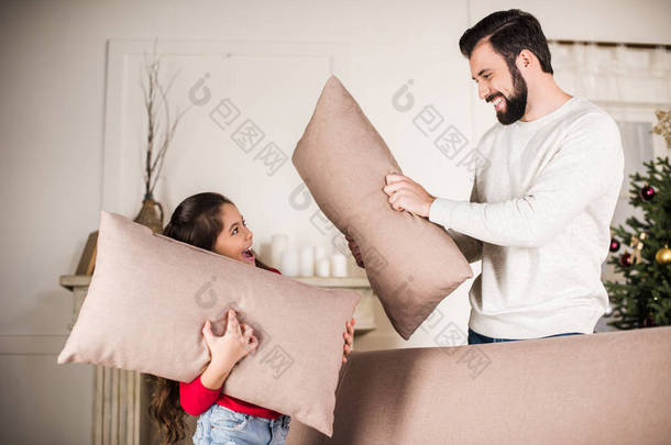 父亲和女儿在家里打枕头 