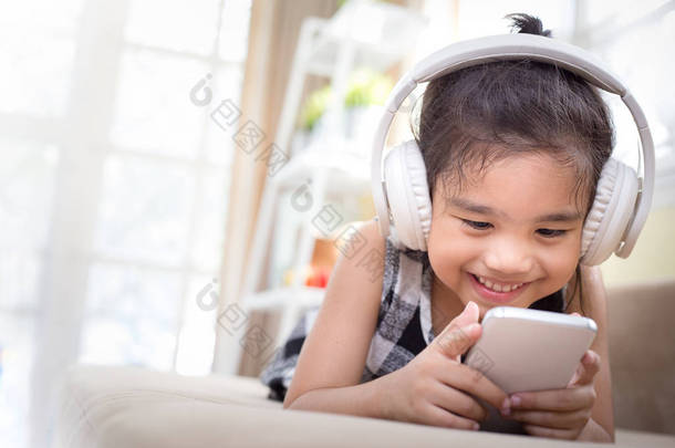 快乐的<strong>亚洲女孩</strong>使用耳机听音乐的智能手机在直播室