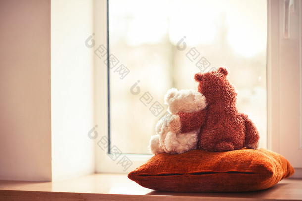 拥抱爱的泰迪熊玩具，坐在窗台上的两个